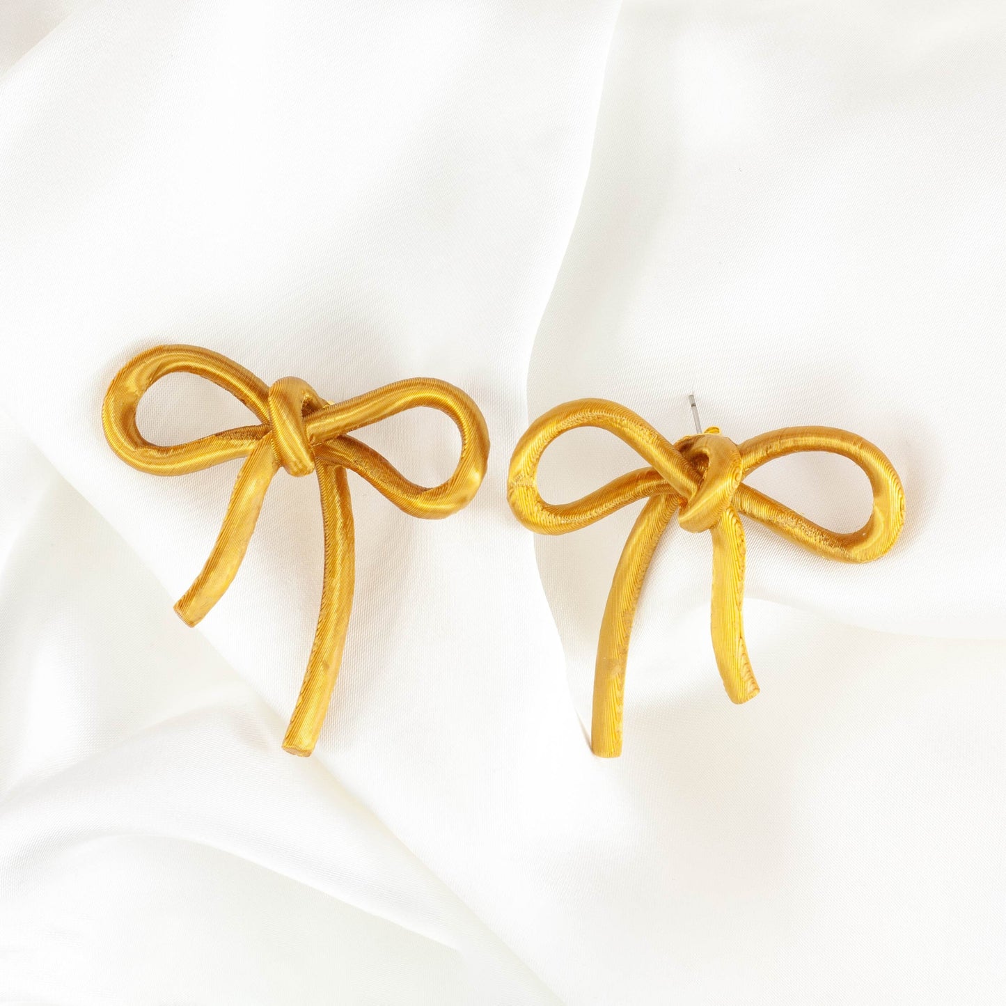 Bow-shaped earrings from the Coquette Collection, in gold silk finish.