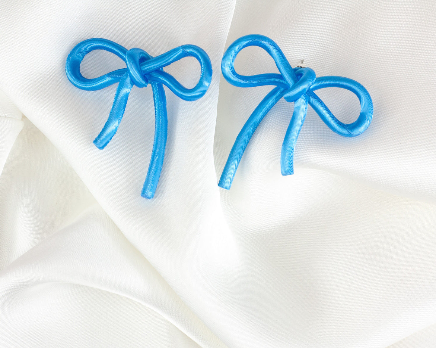 Bow-shaped earrings from the Coquette Collection, in cyan blue with a silk finish.